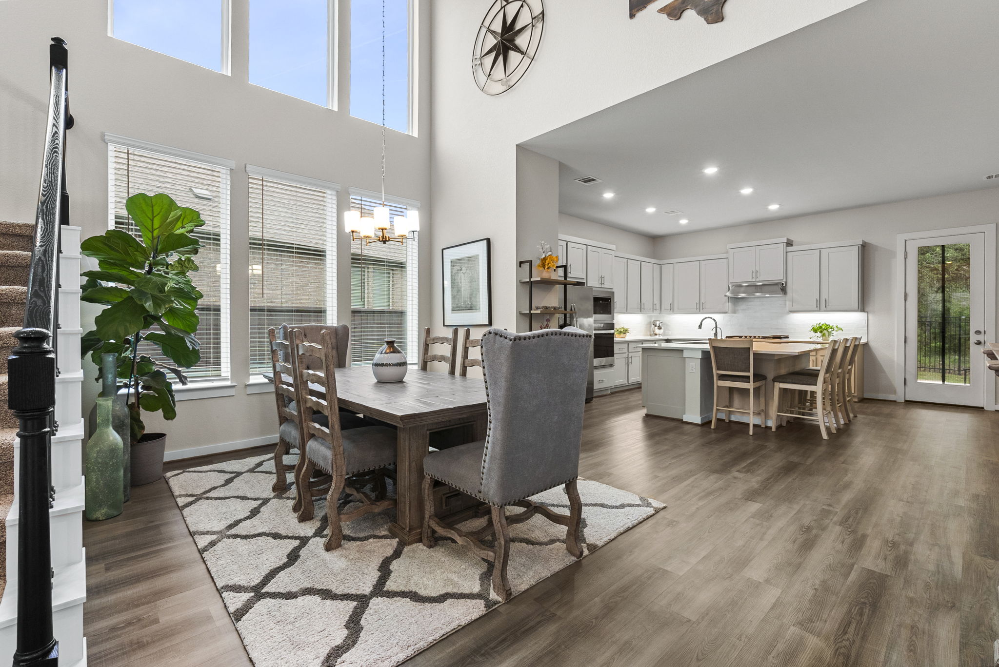 460 Constitution Way Kyle, TX 78640 - Photo 12 of 40 Open-concept living area featuring high ceilings with upper-level windows, wood-finish flooring, and a dining space with a chandelier