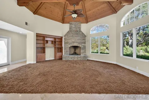 a large kitchen with stainless steel appliances a large counter top a chandelier and living room view