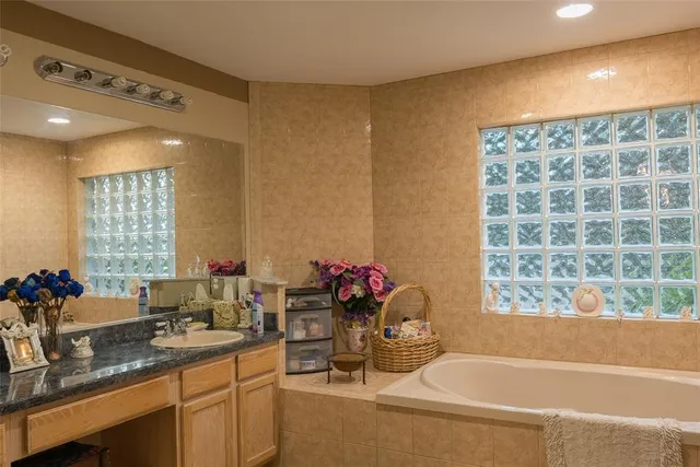 a bathroom with a granite countertop sink and a bathtub