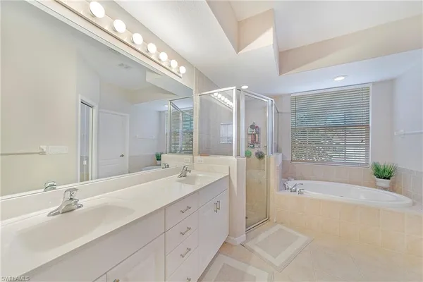 a spacious bathroom with a double vanity sink a large mirror and shower