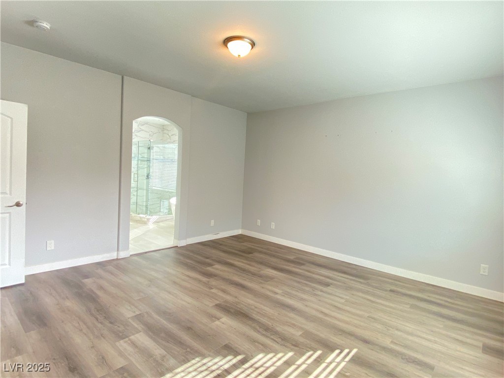 9637 Greensburg Avenue Las Vegas, NV 89178 - Photo 21 of 33 Empty room with arched walkways, baseboards, and wood finished floors