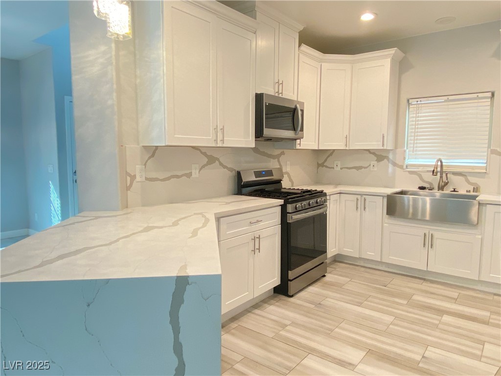 9637 Greensburg Avenue Las Vegas, NV 89178 - Photo 9 of 33 Kitchen featuring light stone countertops, stainless steel appliances, a sink, white cabinets, and decorative backsplash