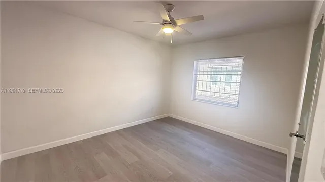 an empty room with a window and a fan