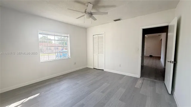 an empty room with wooden floor closet and windows
