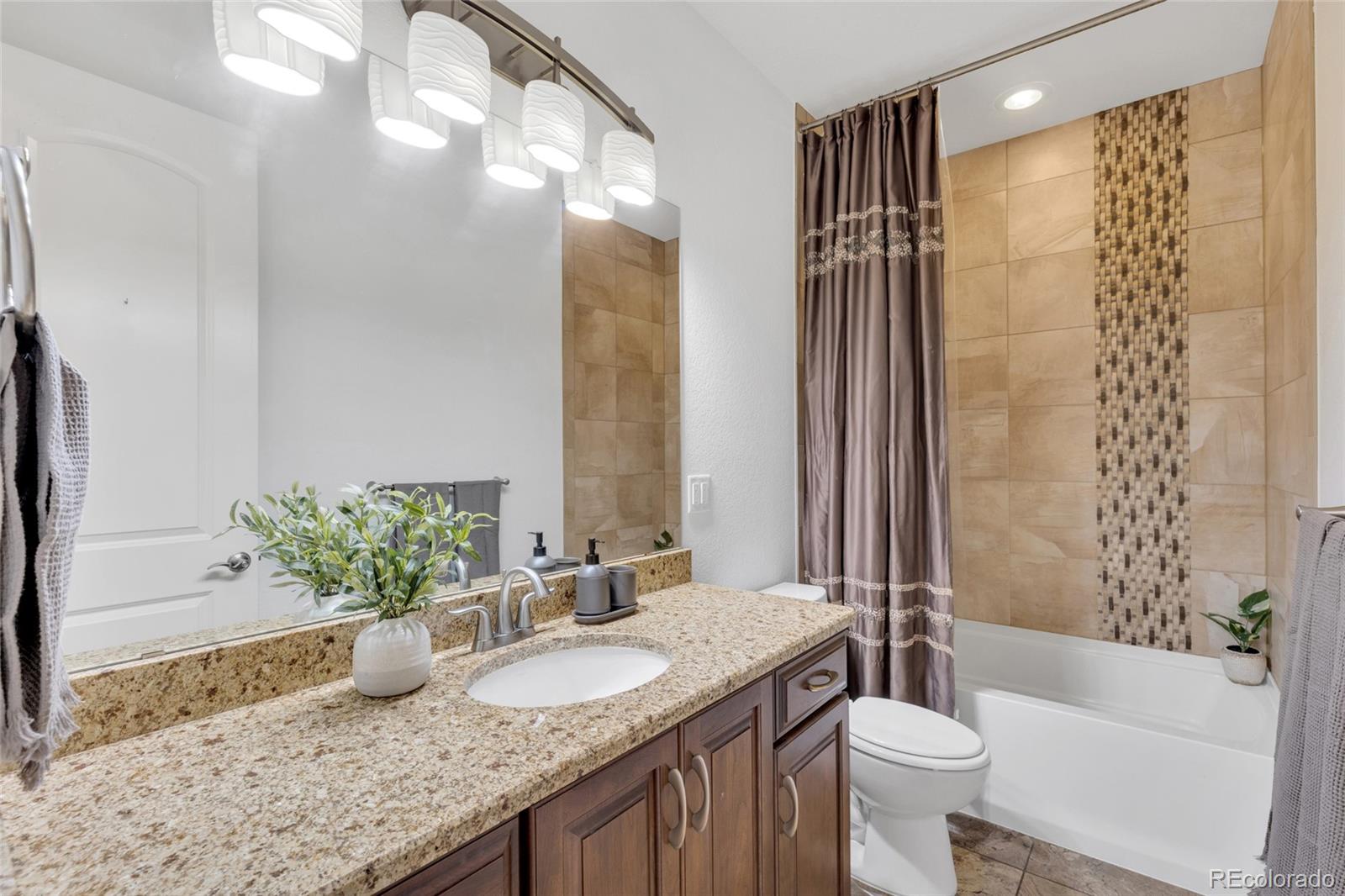 10632 Star Thistle Court Highlands Ranch, CO 80126 - Photo 24 of 50 a bathroom with a granite countertop sink toilet mirror and shower
