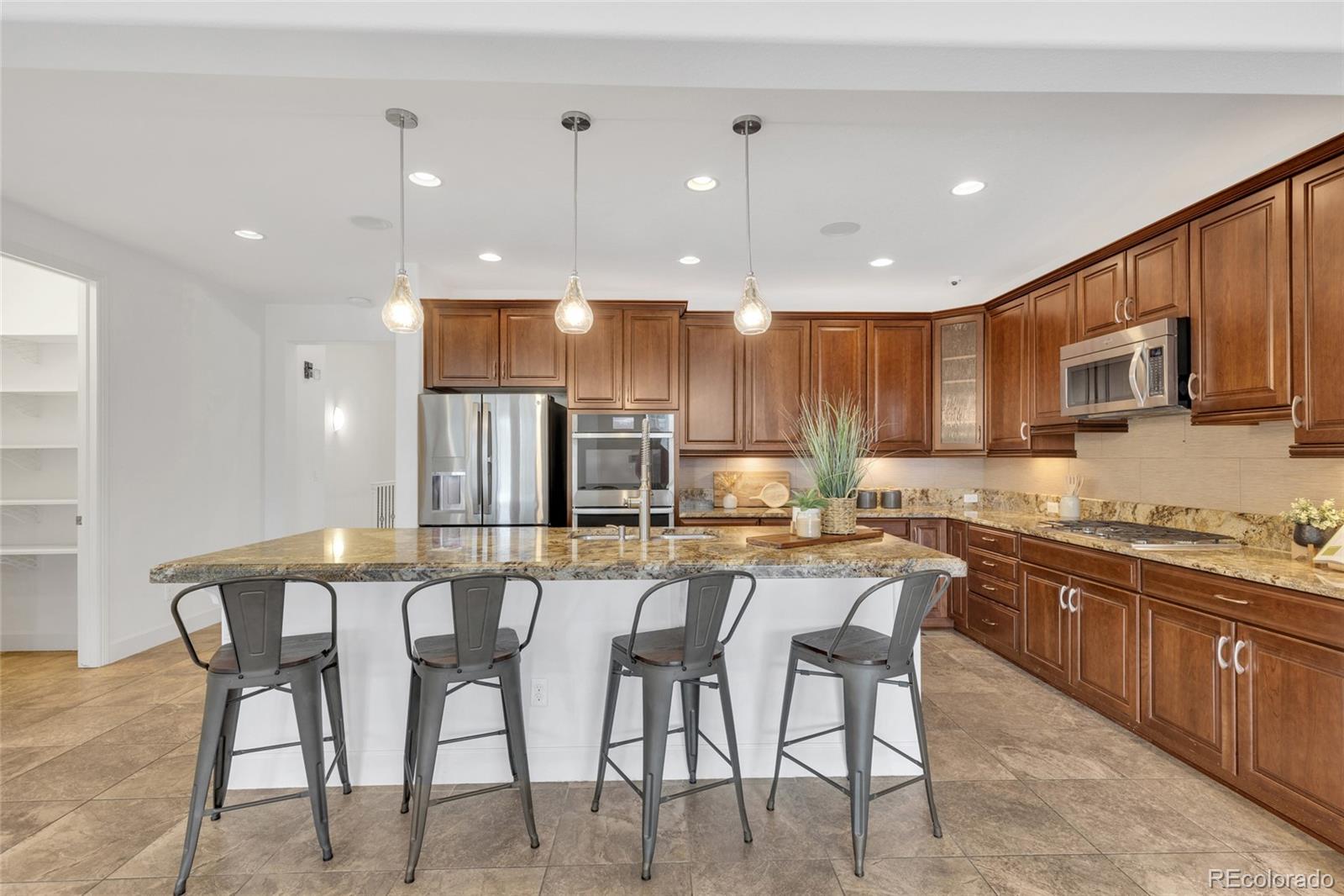 10632 Star Thistle Court Highlands Ranch, CO 80126 - Photo 7 of 50 a kitchen with stainless steel appliances kitchen island granite countertop a sink and cabinets
