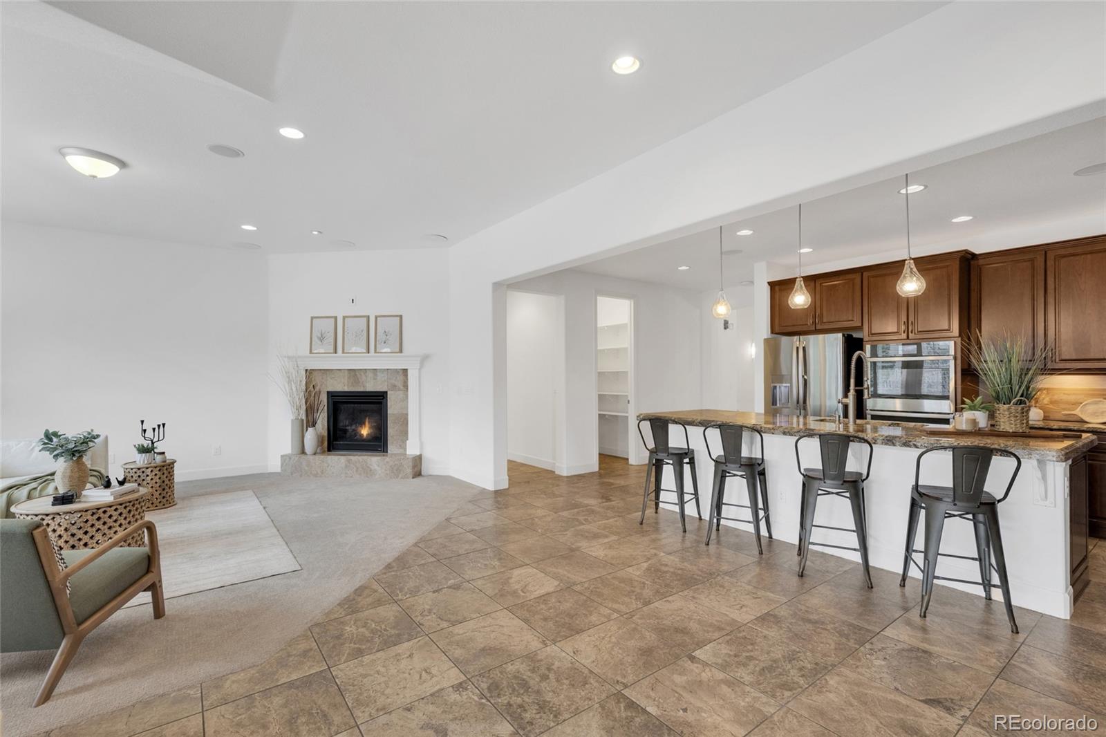 10632 Star Thistle Court Highlands Ranch, CO 80126 - Photo 10 of 50 a living room with furniture a fireplace and a kitchen view