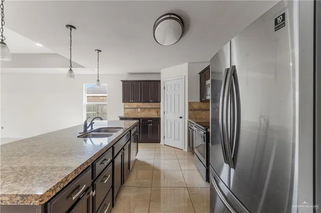 a kitchen with stainless steel appliances granite countertop a sink a stove and a refrigerator