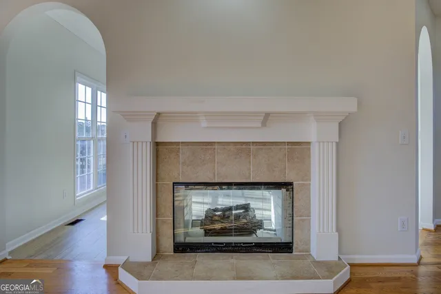 a view of an empty room with a fireplace and a chandelier fan