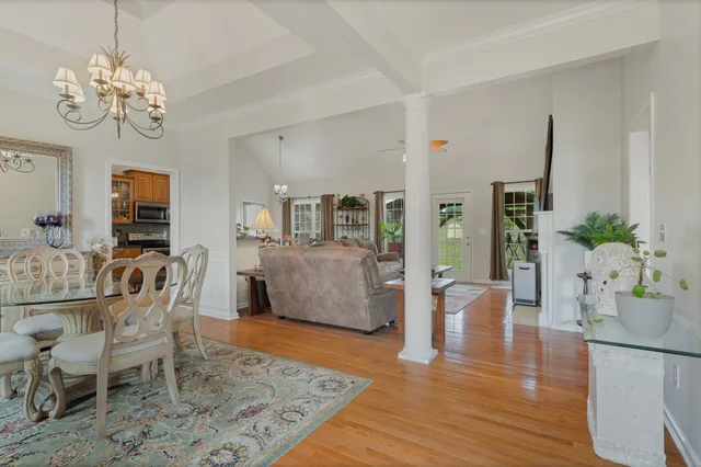 a dining room with wooden floor a chandelier a glass table and chairs