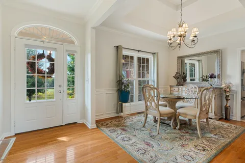 a dining room with chandelier and wooden floor