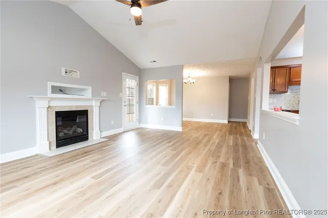 a view of an empty room with wooden floor fireplace and a window