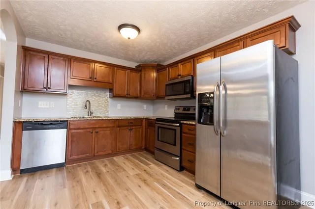 a kitchen with stainless steel appliances granite countertop a refrigerator a sink and a stove
