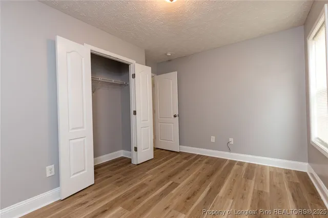 a view of an empty room with wooden floor and closet