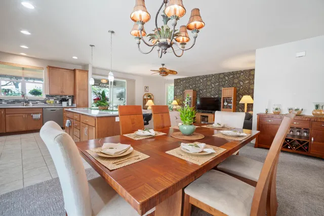 a dining room with wooden floor a chandelier fan a wooden table and chairs