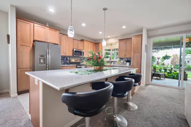 a kitchen with kitchen island a stove a sink a refrigerator and a dining table with wooden floor