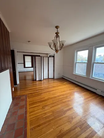 a view of an empty room with a window and wooden floor