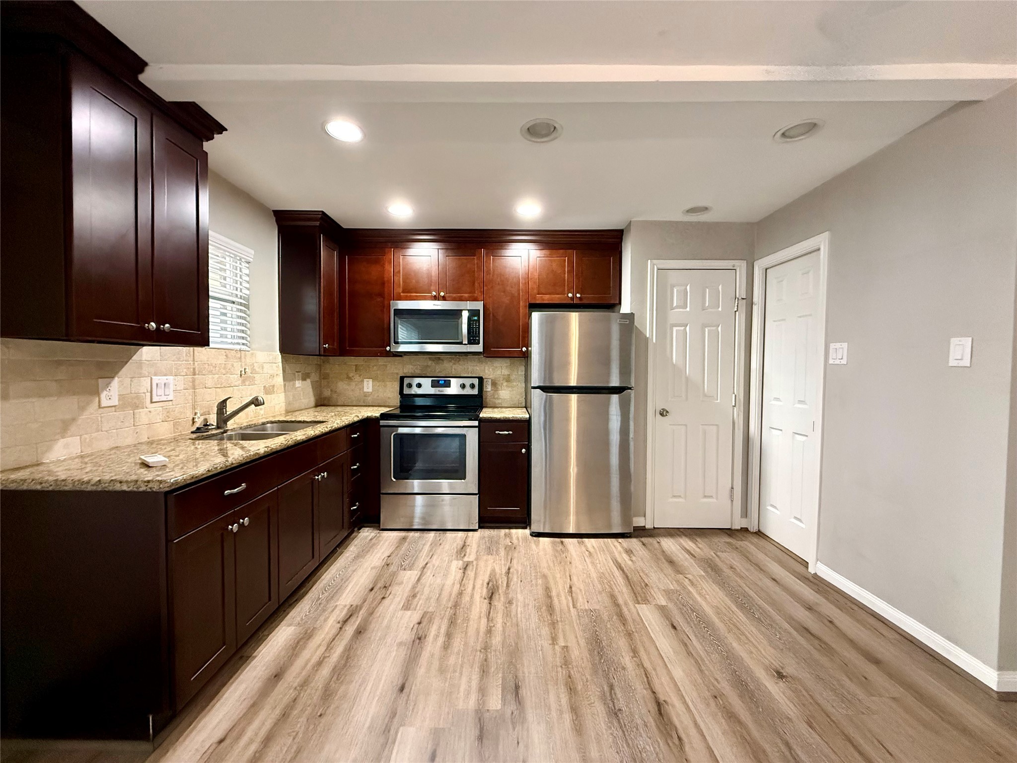 808 West Main Street, Unit 5 Houston, TX 77006 - Photo 4 of 6 a kitchen with stainless steel appliances granite countertop a refrigerator a sink dishwasher a stove and a oven with wooden floor