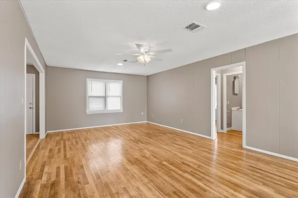 a view of an empty room with window and wooden floor