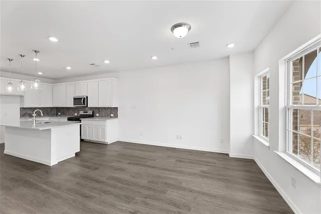 a open kitchen with white cabinets and wooden floor