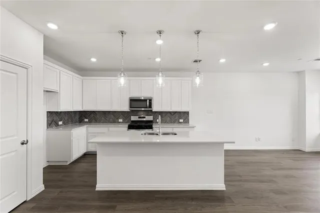 a kitchen with kitchen island a sink stainless steel appliances and white cabinets