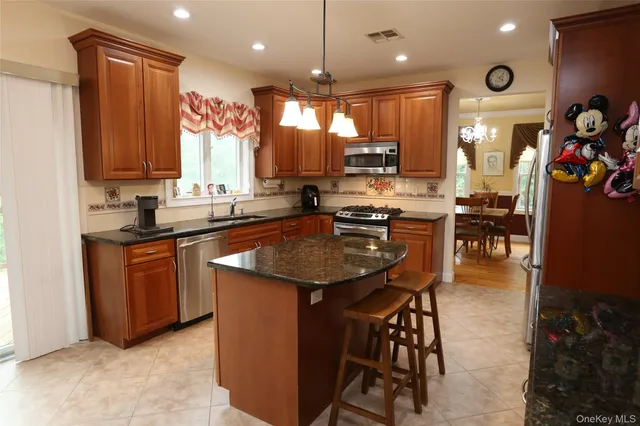 a kitchen with stainless steel appliances granite countertop a stove top oven a refrigerator a sink and a center island