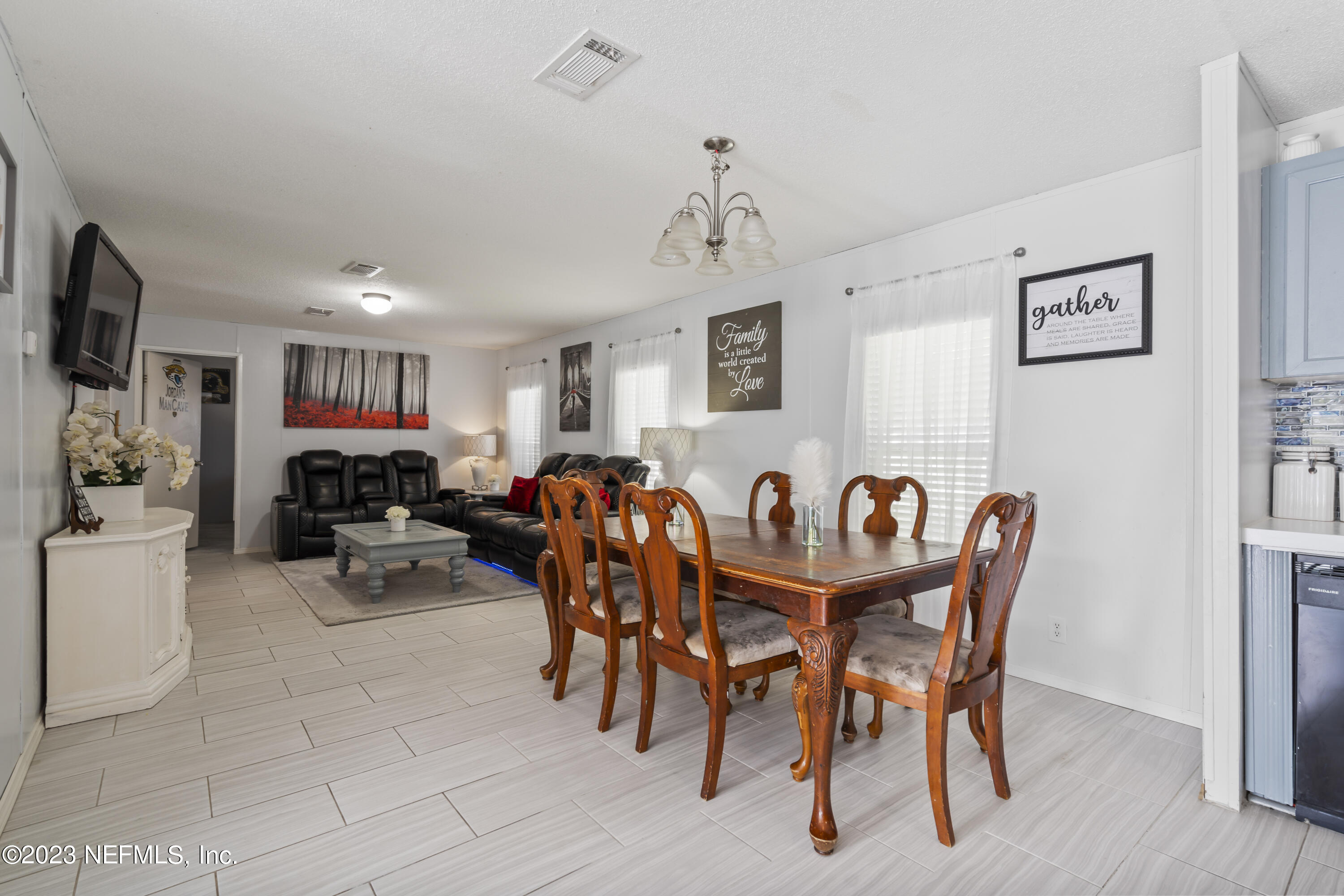 198 Yellow Water Road Baldwin, FL 32234 - Photo 11 of 37 a view of a dining room and livingroom with furniture a flat screen tv a painting and a chandelier