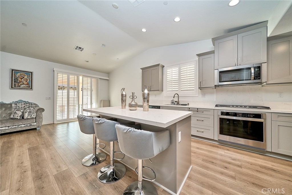 7902 Ravello Court Highland, CA 92346 - Photo 12 of 52 a kitchen with stainless steel appliances granite countertop a stove top oven a sink dishwasher a dining table and chairs with wooden floor
