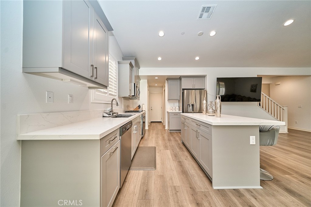 7902 Ravello Court Highland, CA 92346 - Photo 14 of 52 a large kitchen with a large counter top space a sink stainless steel appliances and cabinets
