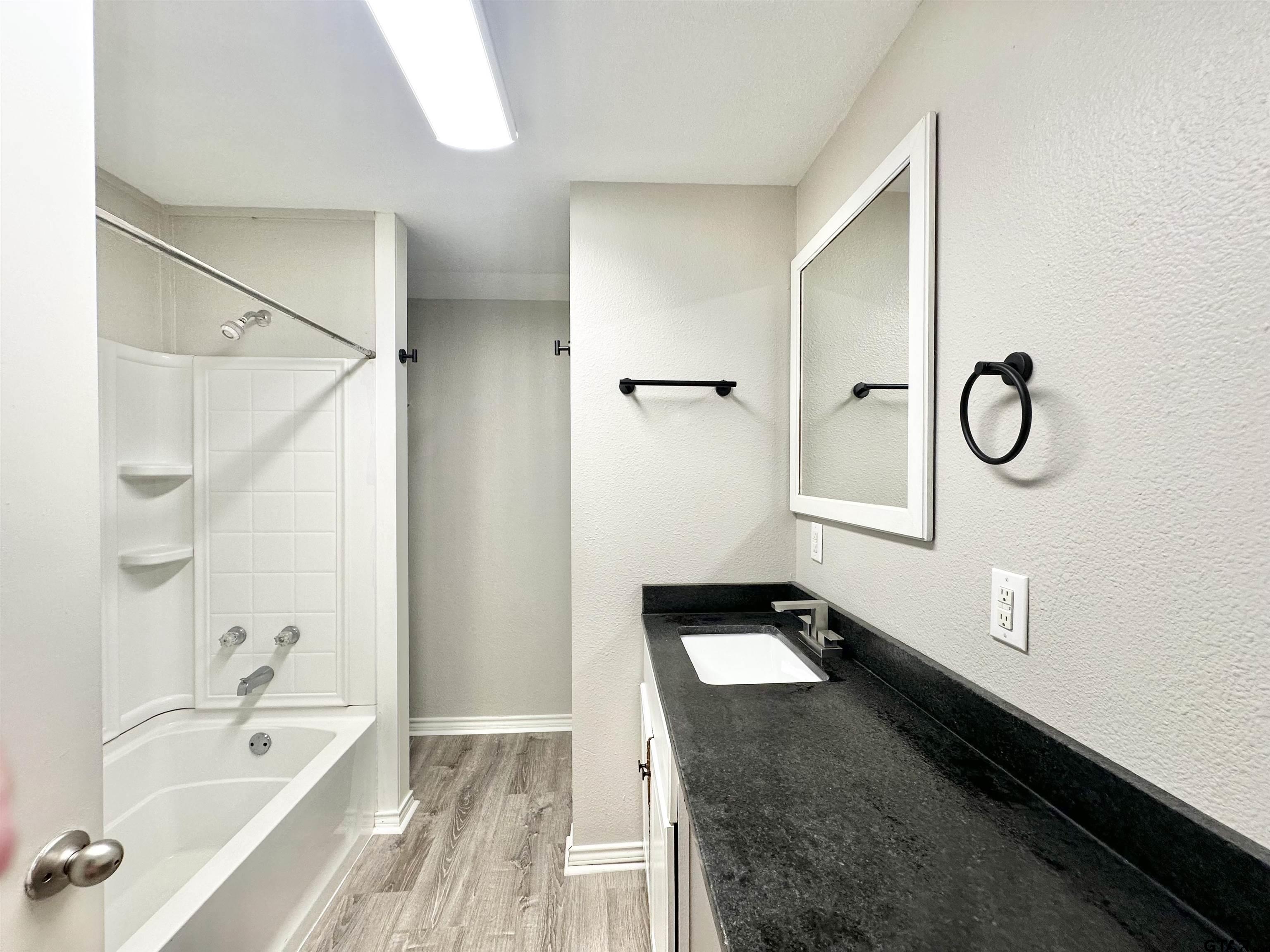 219 Half Street Lindale, TX 75771 - Photo 23 of 33 a bathroom with a granite countertop sink a mirror and a bathtub