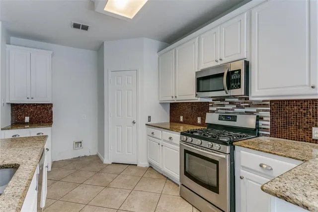 a kitchen with granite countertop a stove top oven microwave and cabinets