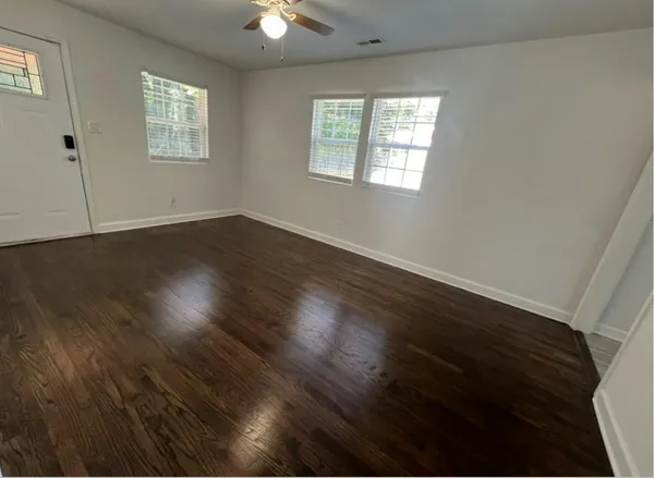 an empty room with wooden floor and windows