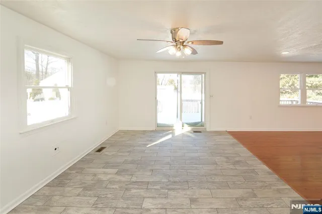 an empty room with windows and fan