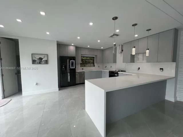 a large white kitchen with a large counter top stainless steel appliances