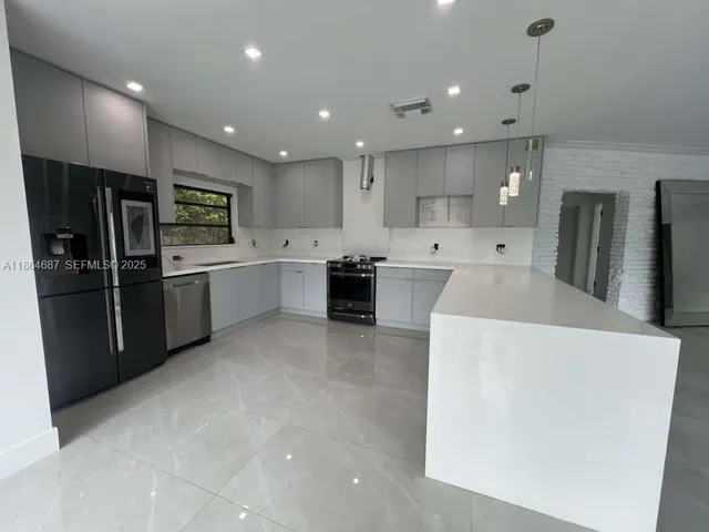 a large kitchen with stainless steel appliances a refrigerator and a sink