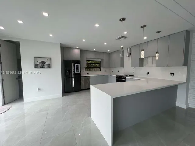 a large white kitchen with a large counter top stainless steel appliances