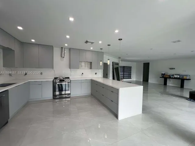 a large white kitchen with wooden floors and white stainless steel appliances