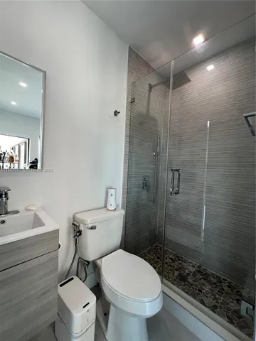 a bathroom with a toilet sink vanity and shower