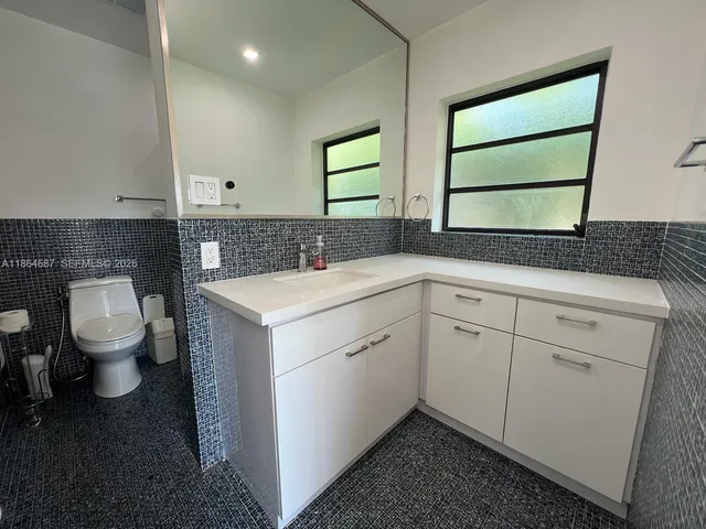 a utility room with a sink a toilet and a mirror