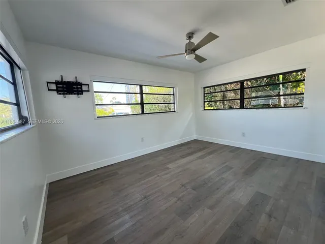 a view of an empty room with a window and wooden floor