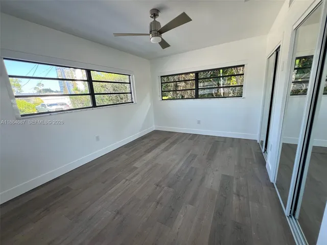 a view of empty room with wooden floor and fan