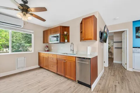 a large kitchen with stainless steel appliances granite countertop a refrigerator oven a sink dishwasher a dining table and chairs with wooden floor