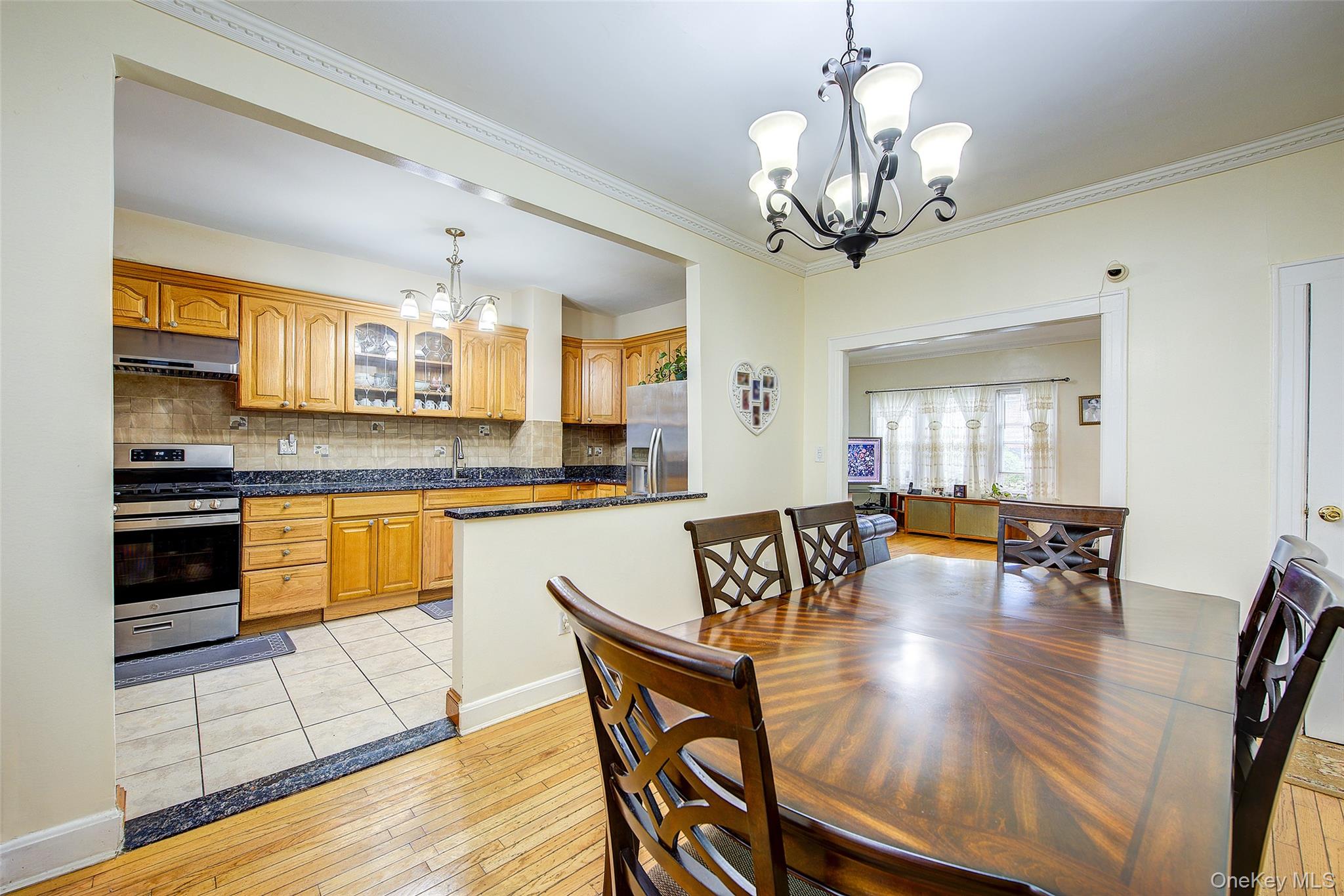 161-10 84th Road Queens, NY 11432 - Photo 14 of 44 a kitchen with stainless steel appliances granite countertop a stove top oven a sink a dining table and chairs with wooden floor