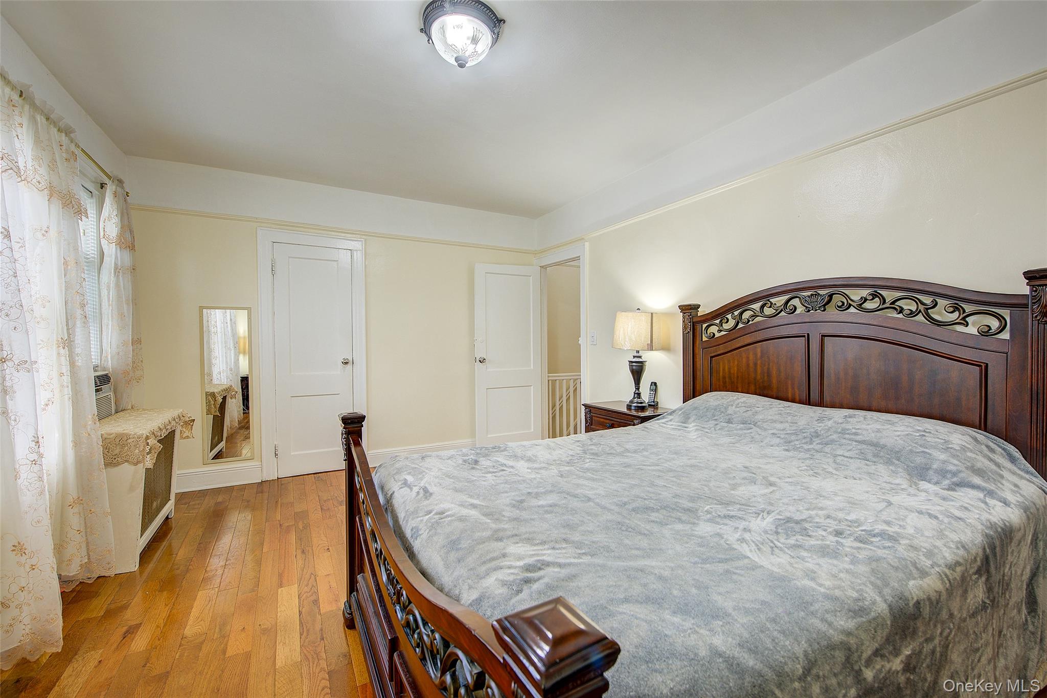 161-10 84th Road Queens, NY 11432 - Photo 26 of 44 a bedroom with a bed and wooden floor