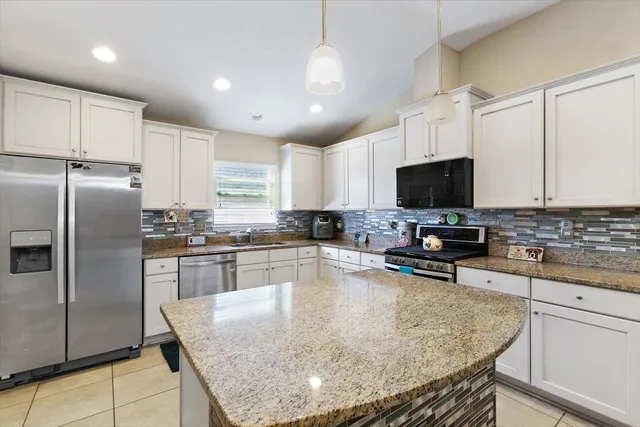 a kitchen with stainless steel appliances granite countertop a sink dishwasher a stove top oven a refrigerator and cabinets