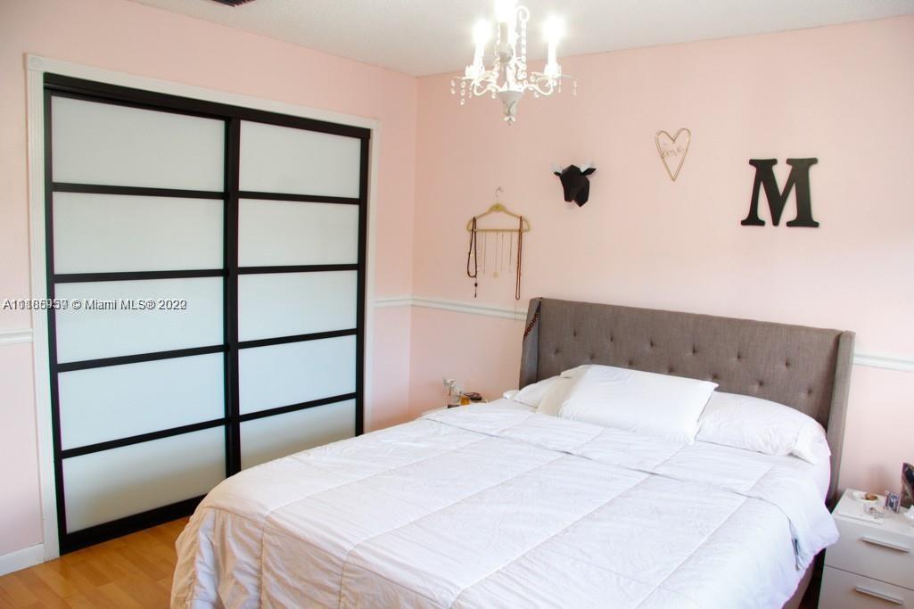 10000 Southwest 147th Court Miami, FL 33196 - Photo 23 of 36 a bedroom with a large bed and a chandelier