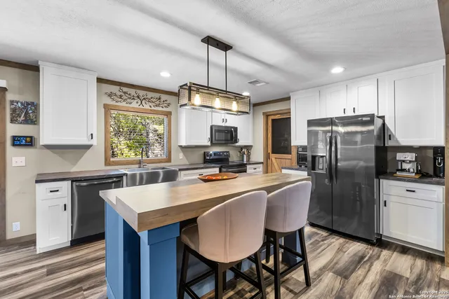 a kitchen with granite countertop a center island stainless steel appliances cabinets and a window