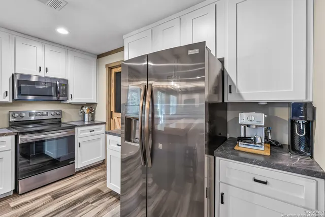 a kitchen with granite countertop a refrigerator stove and microwave