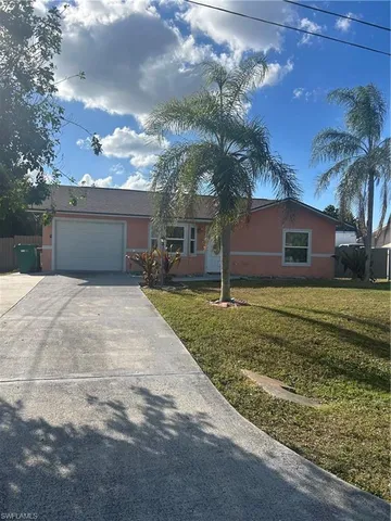 a front view of a house with a yard and palm tree