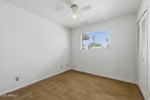 an empty room with windows and fan